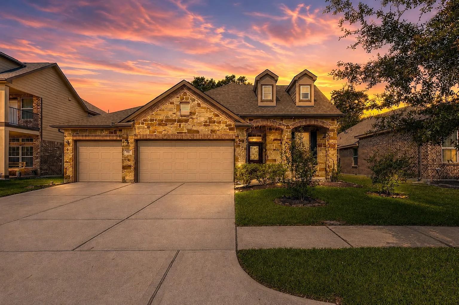 Front exterior of 6531 Hunters Creek Ln in Baytown, Texas at dusk, stone-and-brick facade with a three-car garage