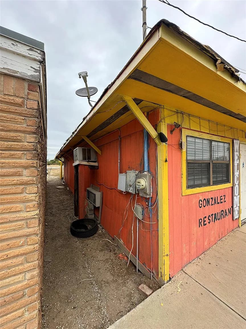 Exterior of the former Gonzalez Restaurant building at 1407 Grand Ave in Big Wells, Texas, with orange and yellow siding