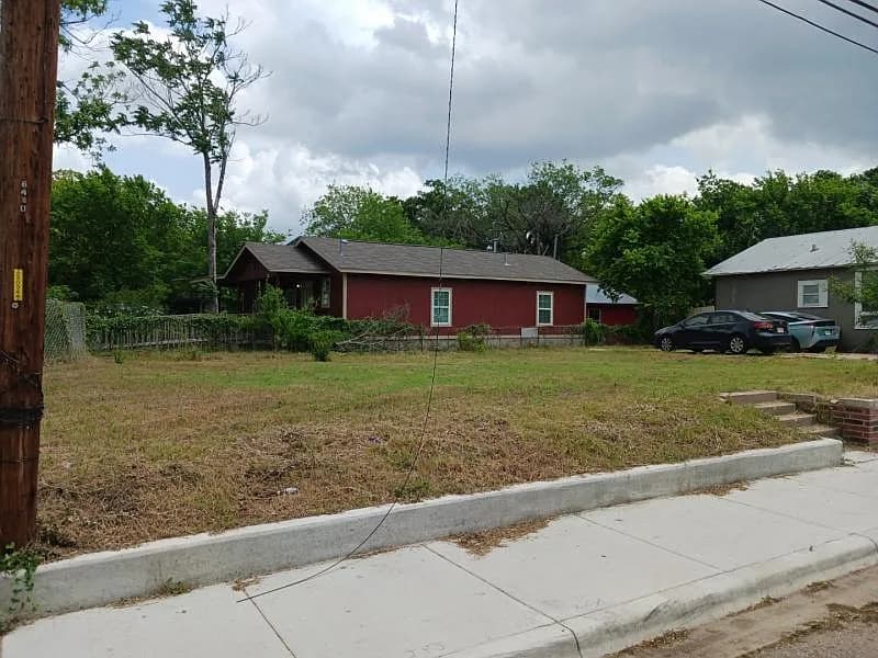 Cleared vacant lot at 6402 Ponca St in East Austin, Texas, with a neighboring red house